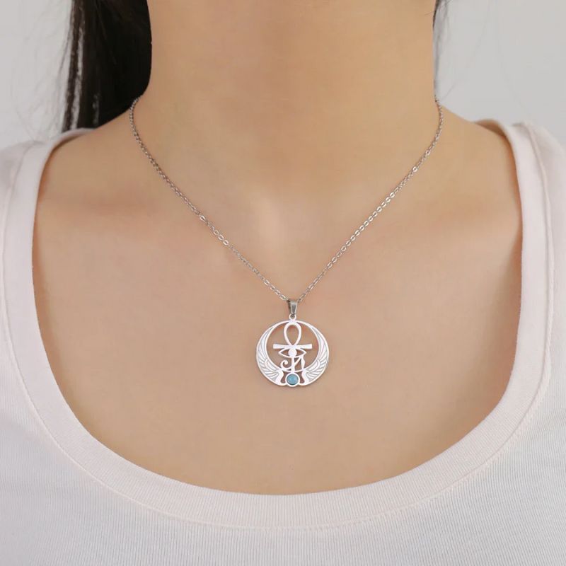 Collier Œil égyptien en acier inoxydable argenté, porté par un modèle en tenue blanche, ajoutant une touche mystique et élégante au style.